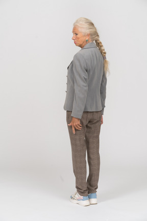 Anciana en chaqueta gris de pie en el perfil