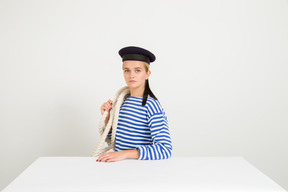 Marinaio femminile seduto di profilo con la corda sopra la spalla