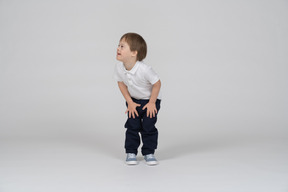 太ももに手を置いて立っている小さな男の子
