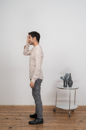 一个穿休闲服的男人的侧视图,透过手指看