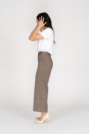 彼女の頭に触れているブリーチとtシャツの若い女性の側面図